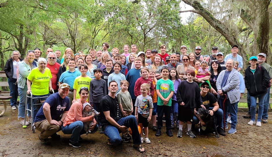 Dozens of UPKUDO family members gathered in front of trees in the park